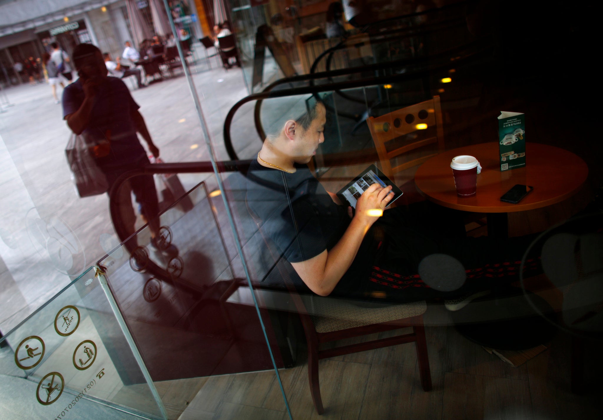 A man surfs the Internet on his tablet device at a coffee shop in downtown Shanghai, 2013.
