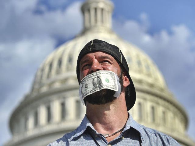 A protester covers his mouth with a dollar bill as he joins others in a demonstration in Washington, DC
