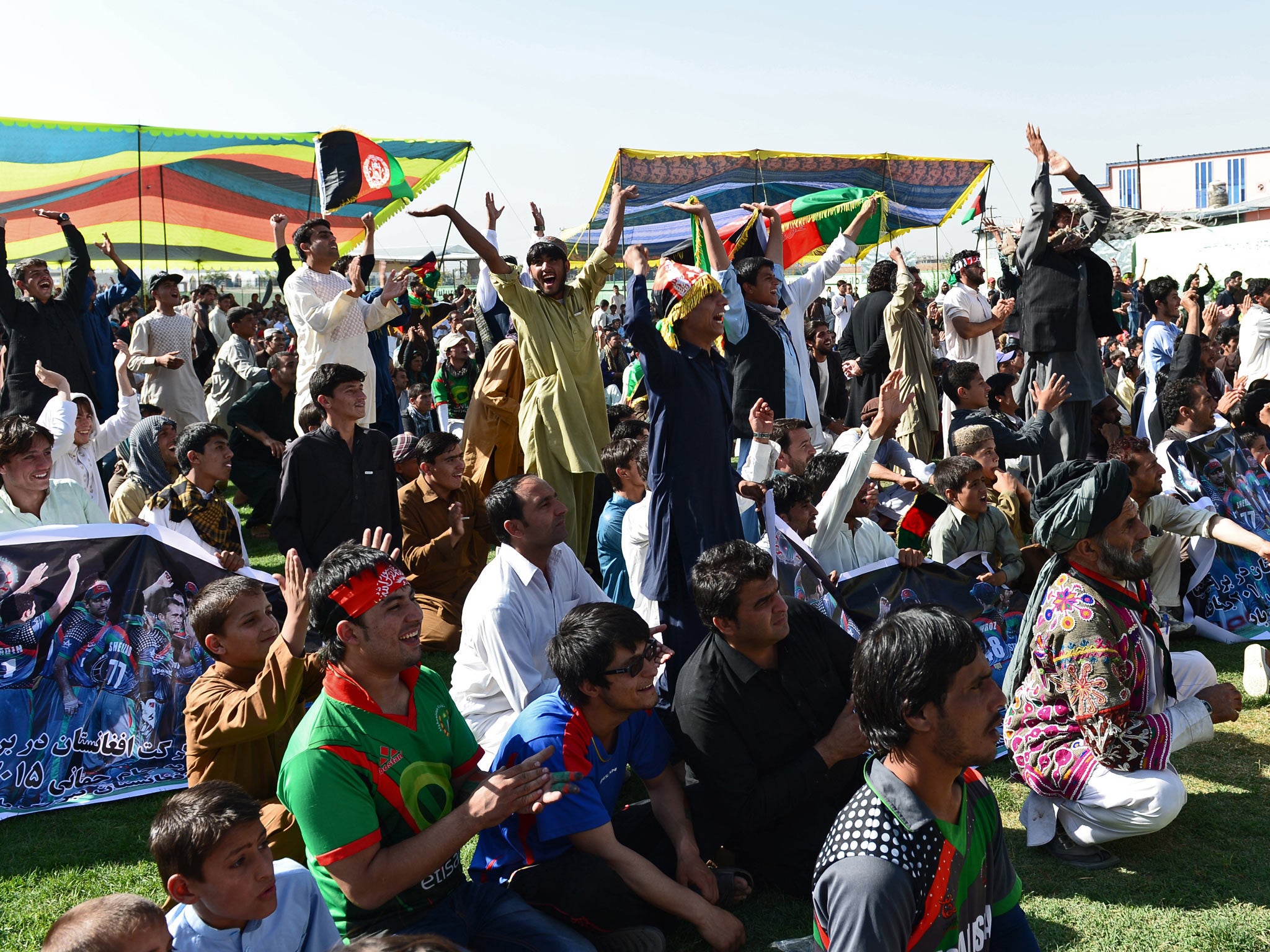 Afghan cricket fans celebrate runs by their team as they watch the Afghanistan and Kenya match on a screen at the International Cricket Stadium in Kabul