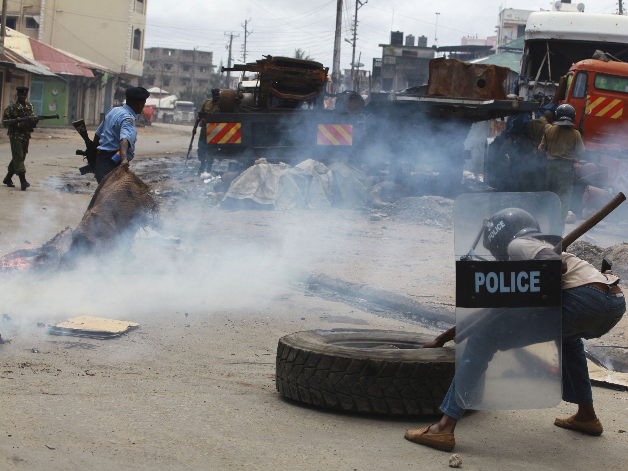 A police officer clears barricades erected by demonstrators during riots following the killing of an Islamic cleric at Kenya's coastal city of Mombasa