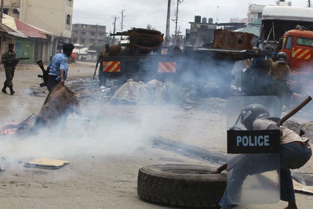 A police officer clears barricades erected by demonstrators during riots following the killing of an Islamic cleric at Kenya's coastal city of Mombasa