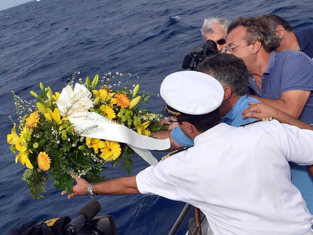 Local fishermen and boat crewmen throw a wreath into the waters off Lampedusa harbour to honour those who lost their lives when a boat carrying migrants sank here
