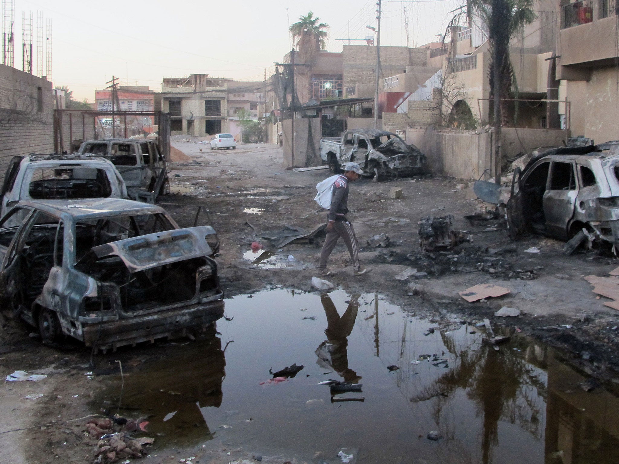 An Iraqi man inspects the aftermath of a bombing in the Baghdad al-Jadidah district,
