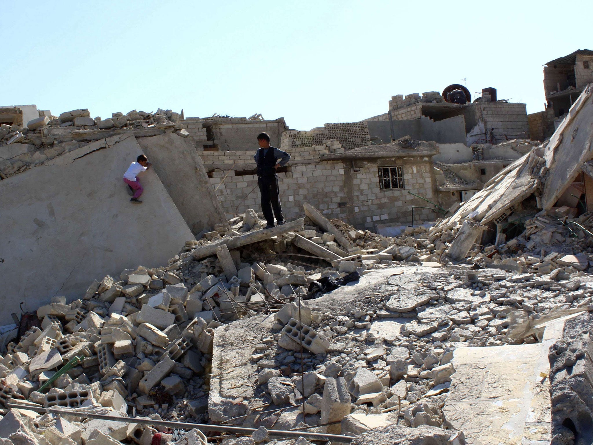 Boys play on debris from damaged buildings in the Duma neighbourhood in Damascus