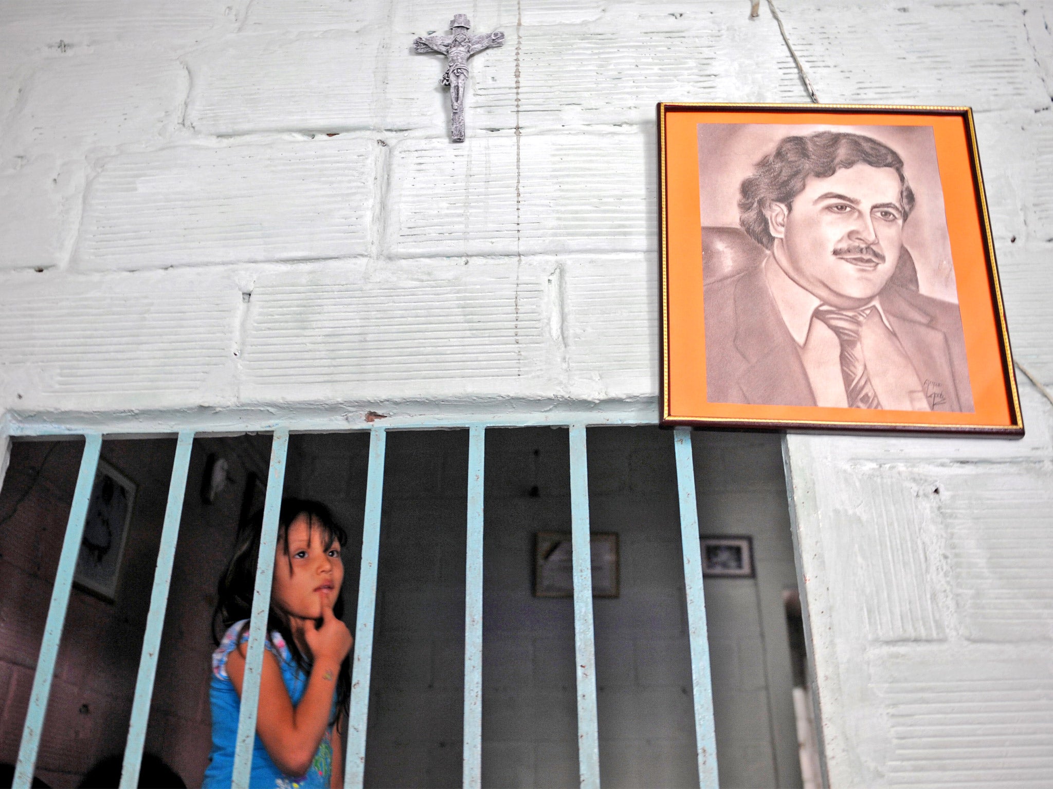 A girl stands by a portrait of Pablo Escobar in Medellin