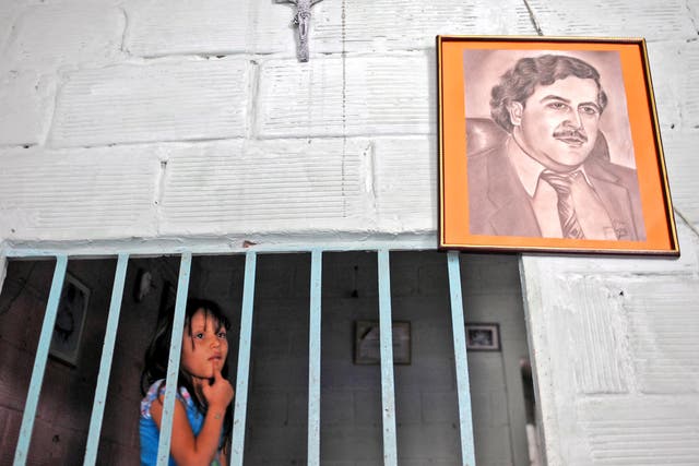 A girl stands by a portrait of Pablo Escobar in Medellin