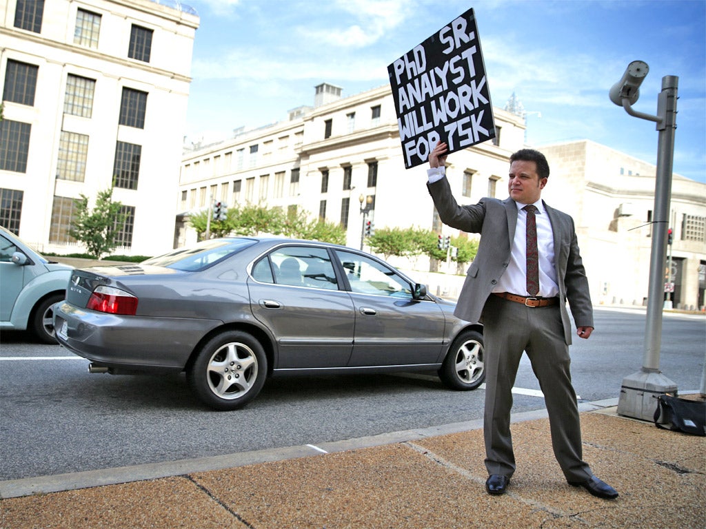 Matthew Giarmo of Alexandria, Virginia, holds up a sign seeking a job on a street corner in Washington, DC