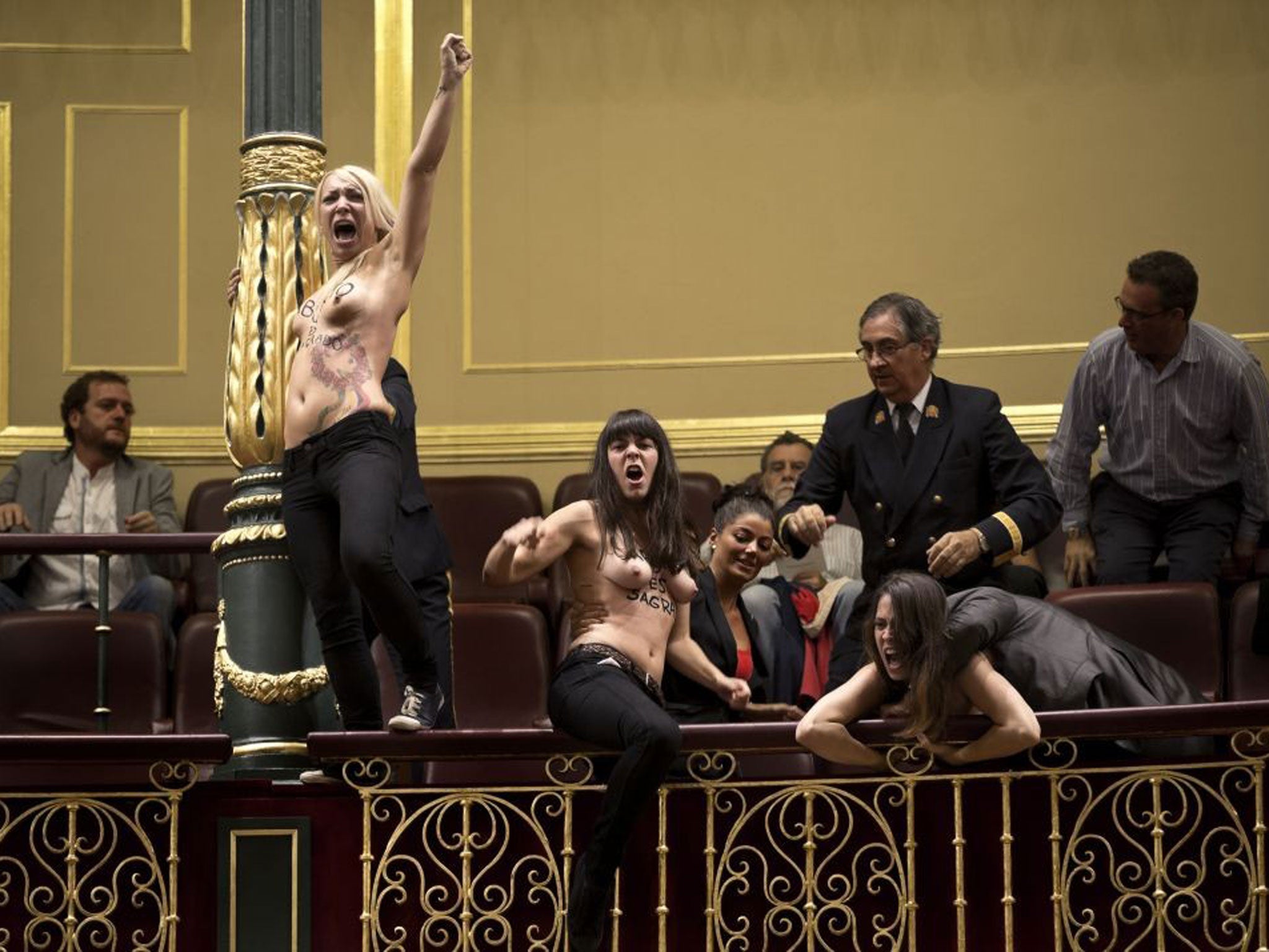 Activists from the women's movement Femen demonstrating in the Spanish parliament against the government's conservative new abortion law, with 'Abortion is Sacred' written on their bodies