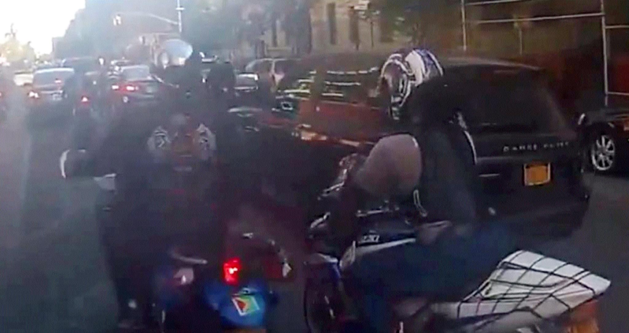 A screen grab from video shows motorcyclists ride alongside a sport utility vehicle