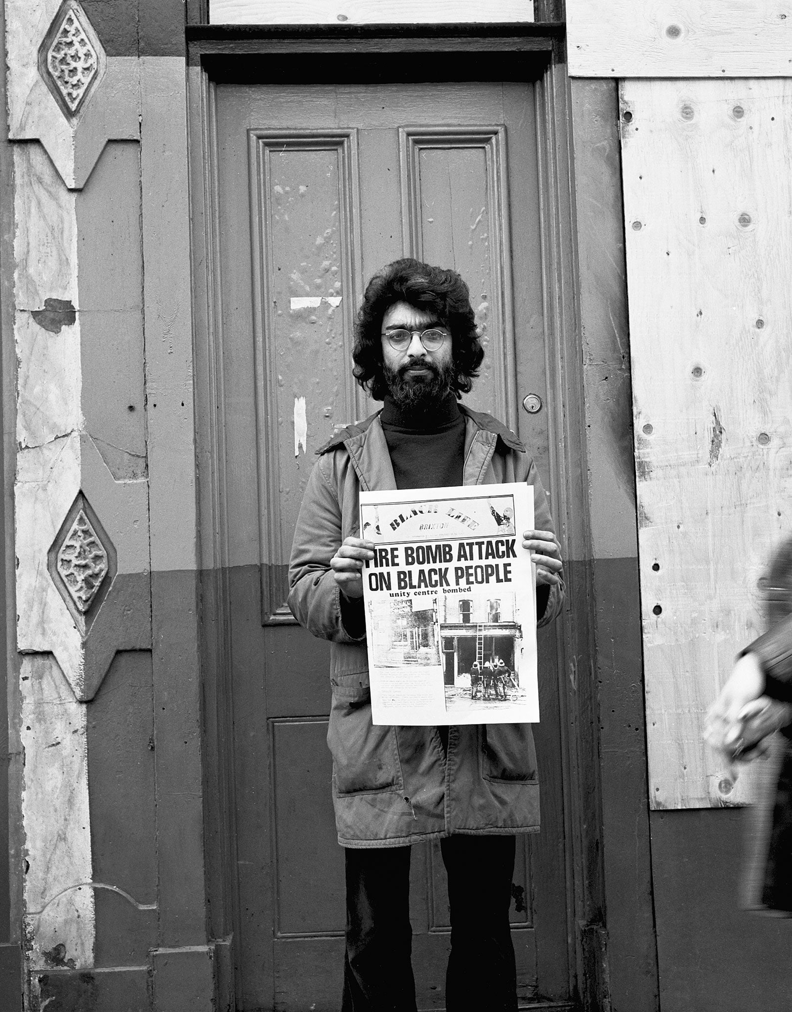 Farrukh Dhondy holds up a newspaper detailing the fire-bombing of his home