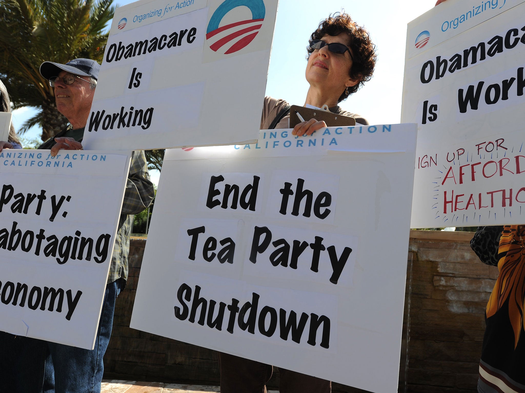 Supporters of the Affordable Healthcare Act hold posters critical of the Tea Party