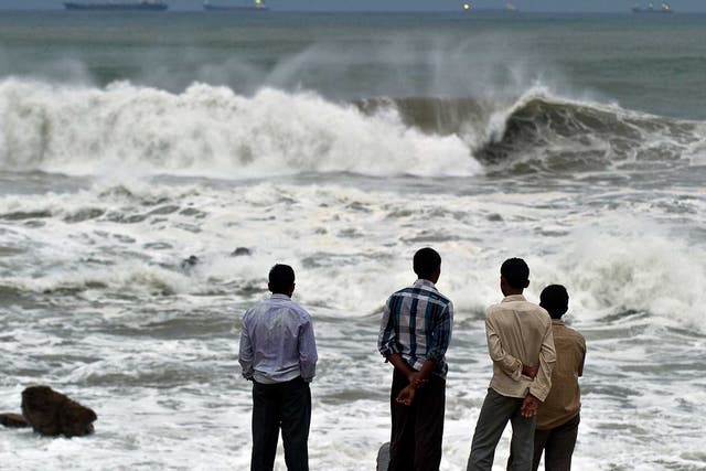 Locals watch as high tidal waves hit the coastline in Visakhapatnam on Saturday morning