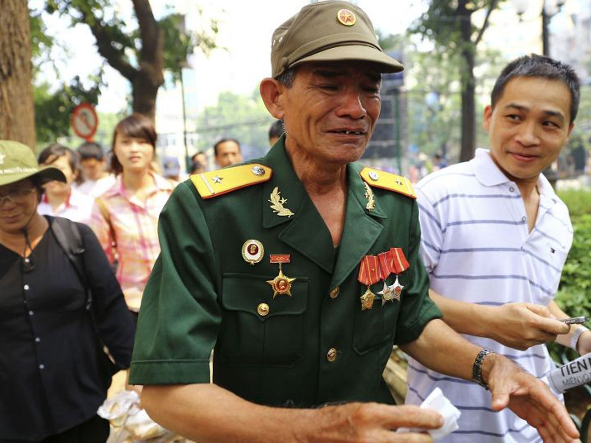 A Vietnamese war veteran (C) cries as he proceeds to the National Funeral House for the funeral service of late general Vo Nguyen Giap, in Hanoi 12 October, 2013