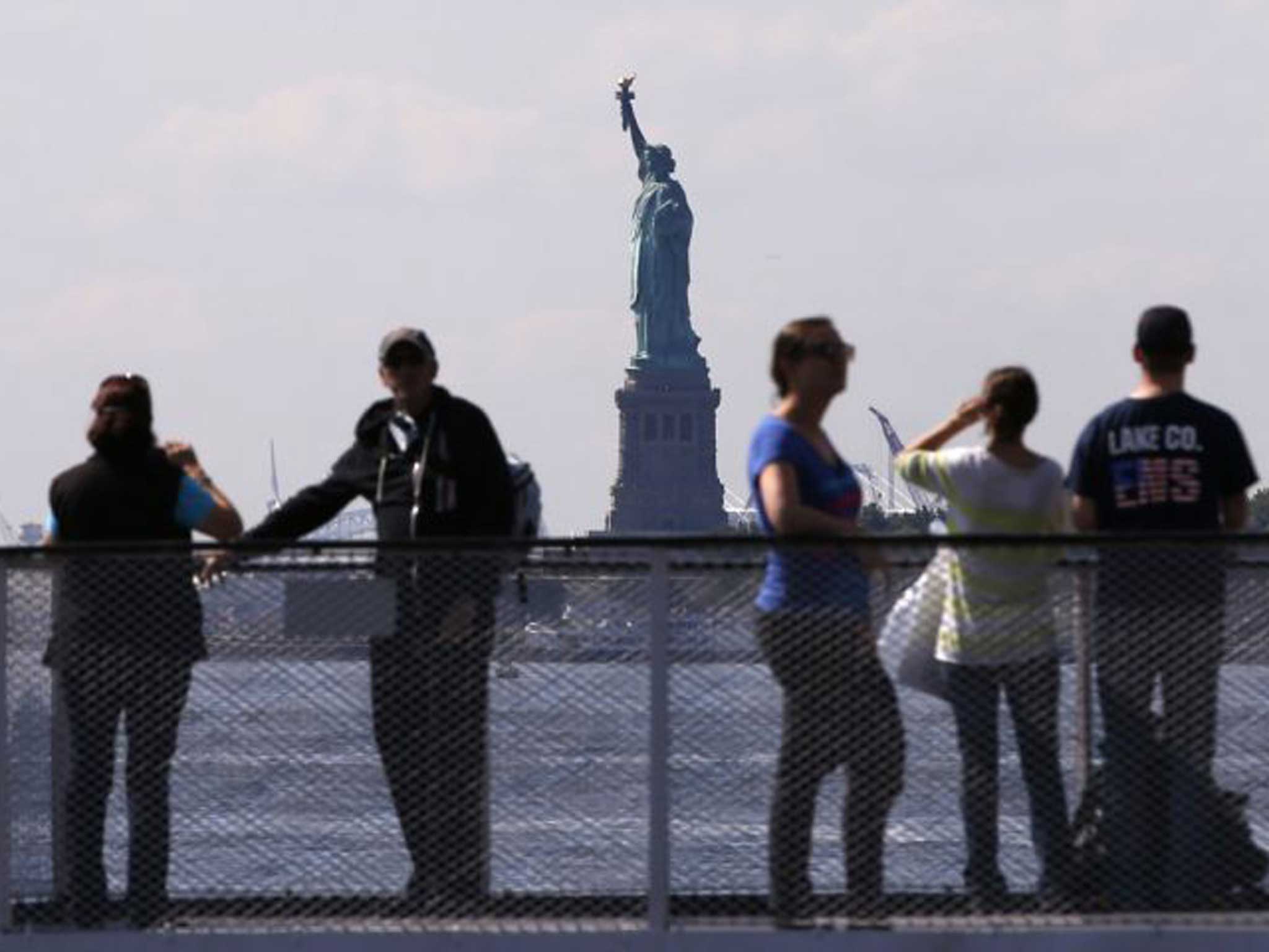 Tourists pause to view the Statue of Liberty from the deck of a Liberty Island ferry boat at Battery Park in New York 
