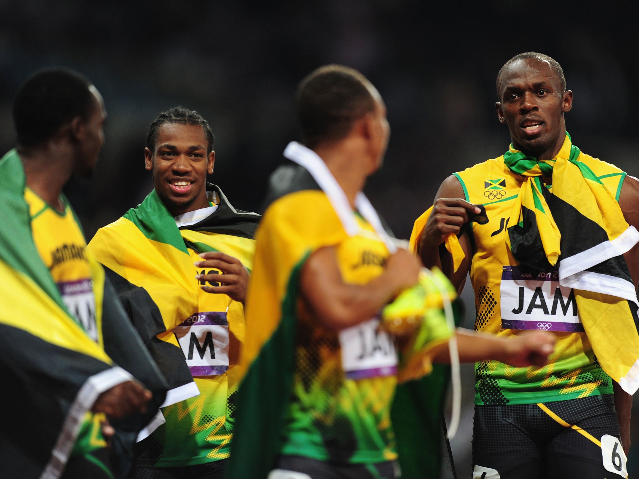 Yohan Blake, Usain Bolt, Nesta Carter and Michael Frater of Jamaica celebrate next to the clock after winning gold and setting a new world record of 36.84 in the 100m relay at the Olympics
