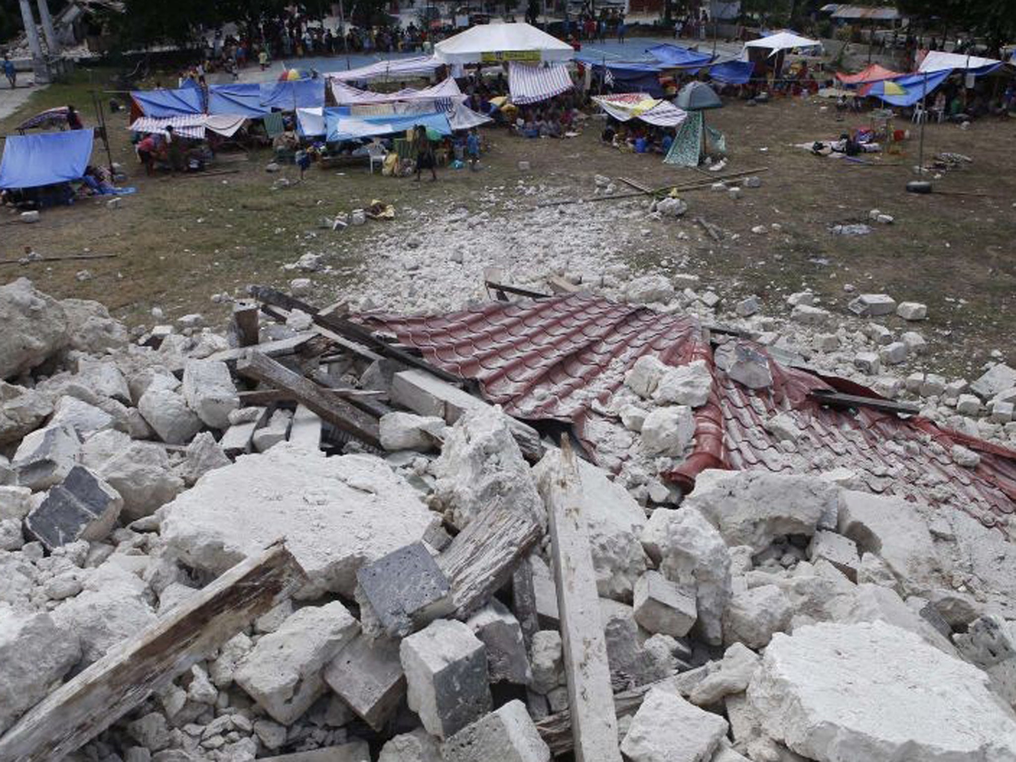 Residents stay in makeshift shelters near the rubble of the collapsed centuries-old Our Lady of Light church in Loon, Bohol