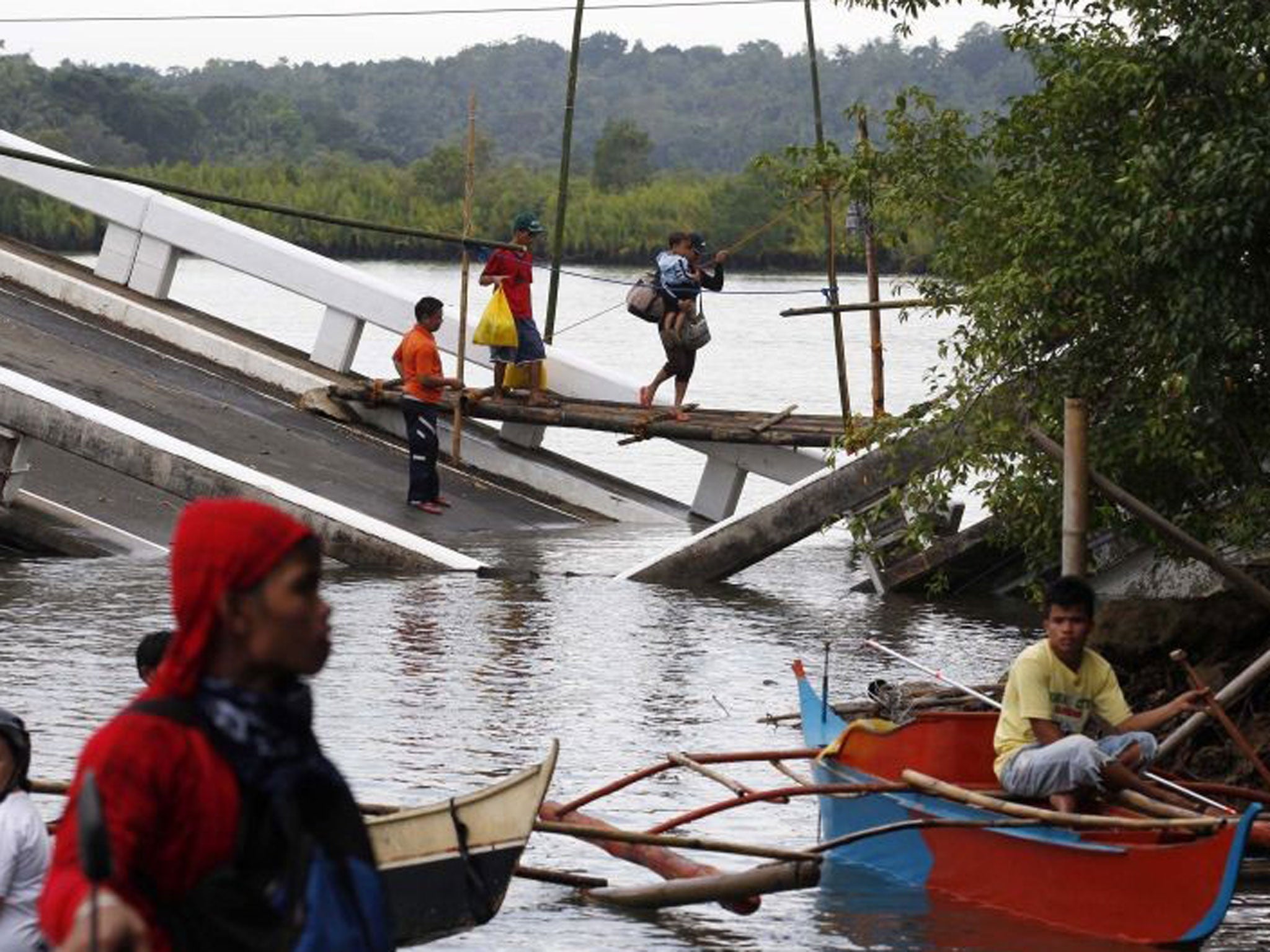 Filipino residents cross on a makeshift bridge, a damaged Avatan Bridge