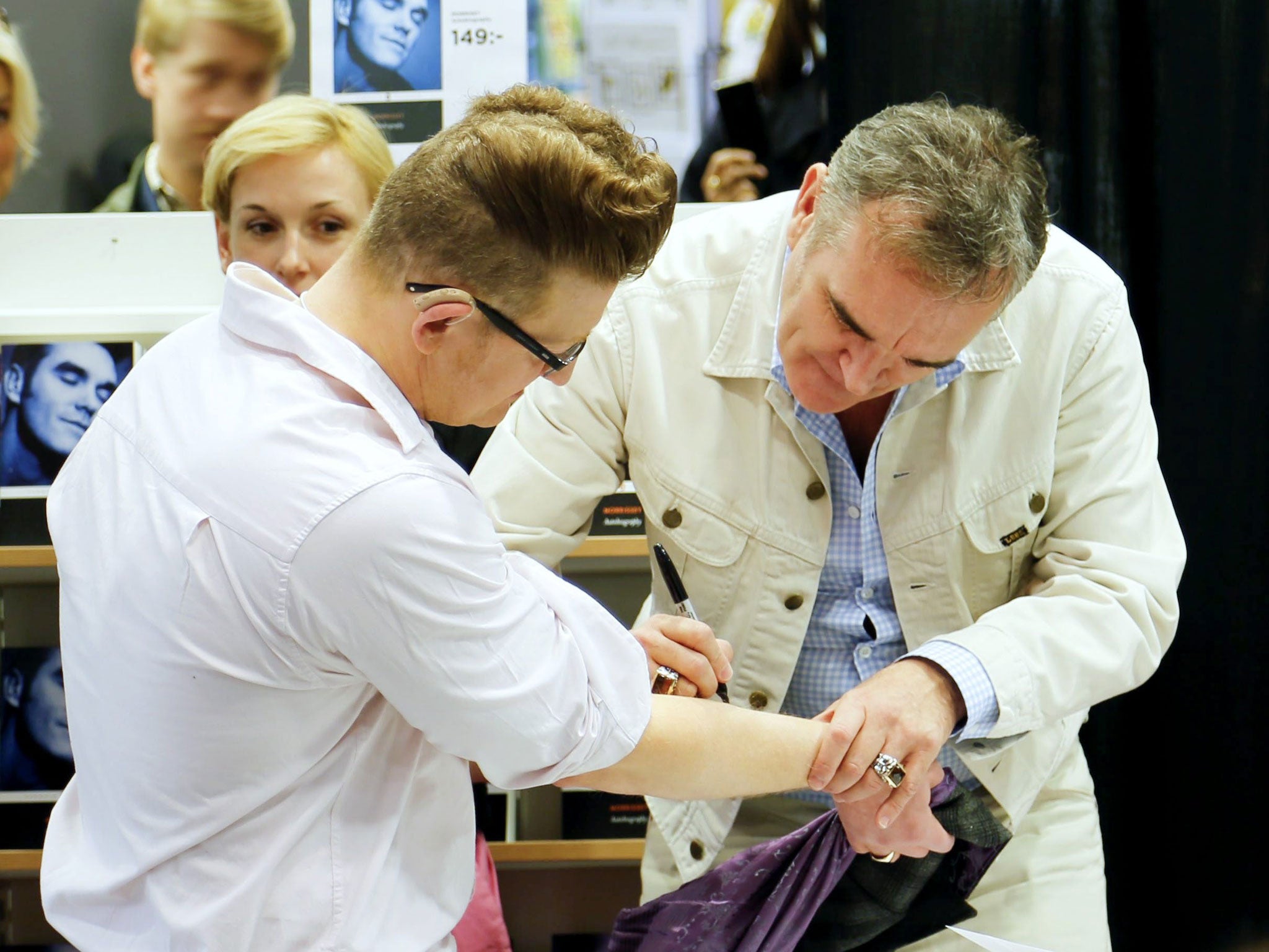 Morrisey, right, signing an autograph on one of his fan's arms