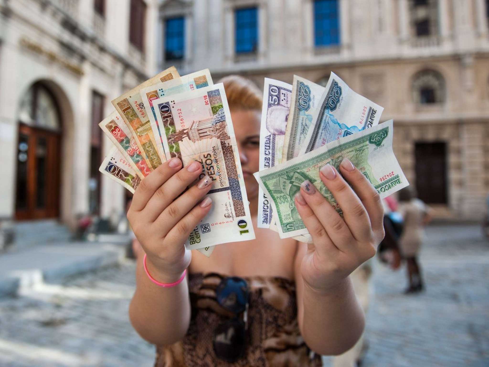 A Cuban shows Cuban Pesos CUP (Left hand) and Convertible Pesos CUC (Right hand)