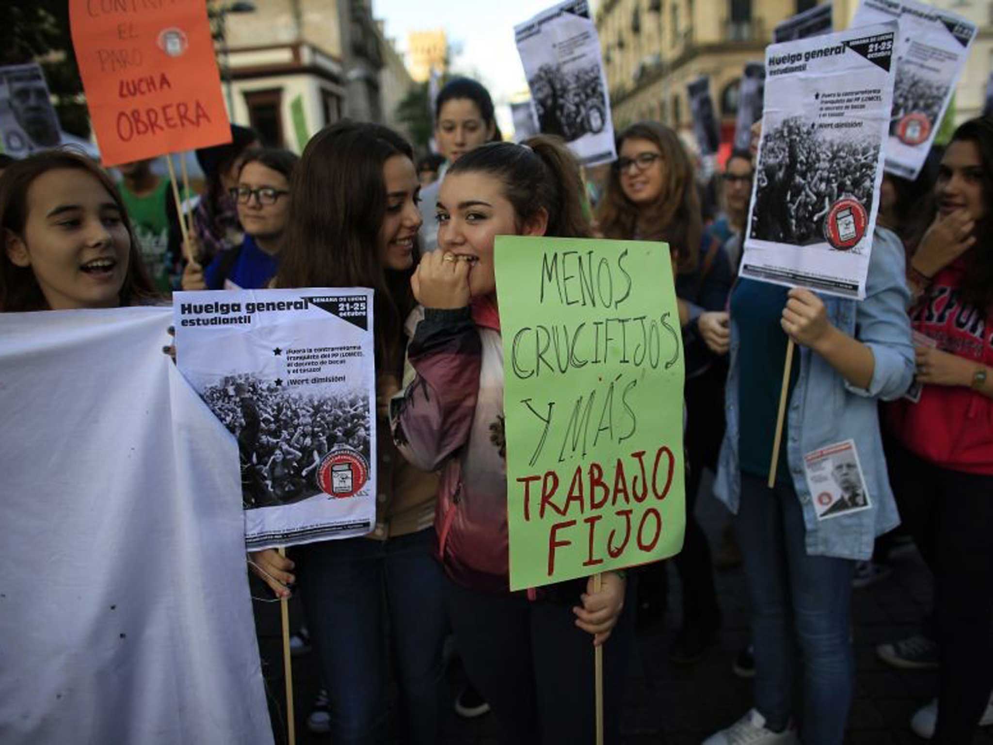 Spanish students hold signs in Seville saying: 'less crucifixes, more jobs' today