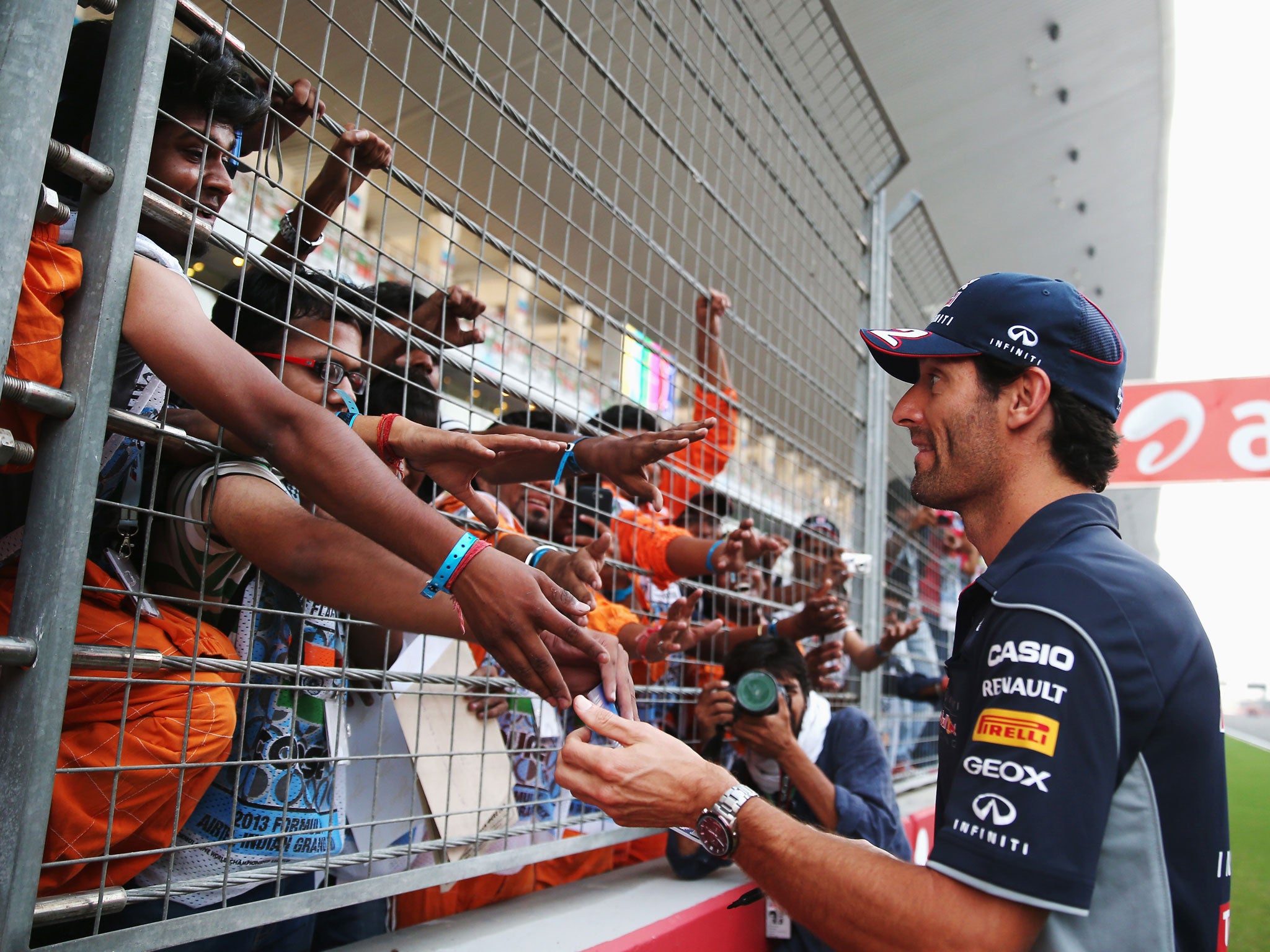 Mark Webber of Australia and Infiniti Red Bull Racing signs autographs for fans during previews for the Indian Formula One Grand Prix