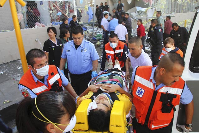 Paramedics move an injured person to an ambulance outside a sweet factory in Ciudad Juarez, Mexico