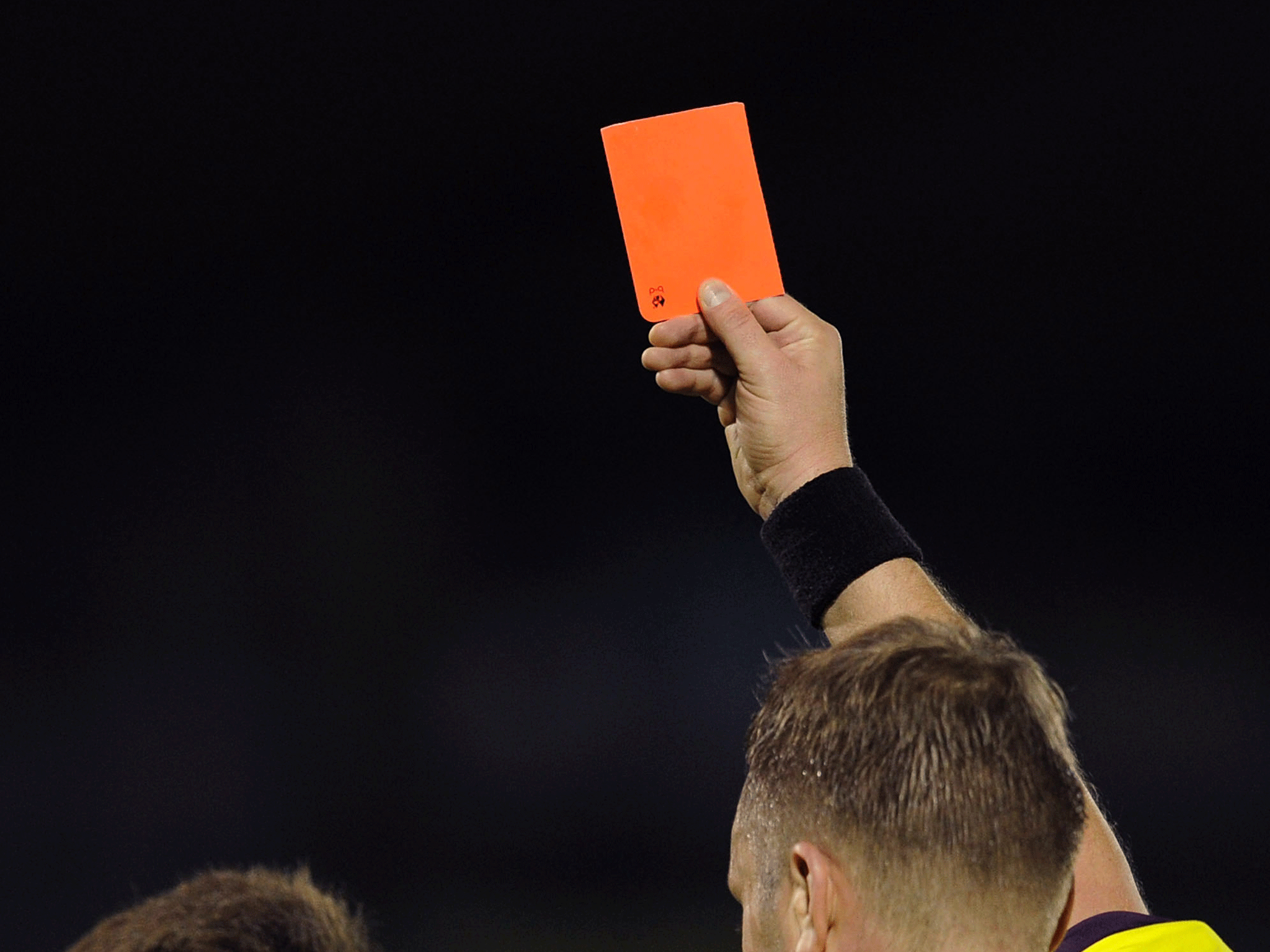 A referee brandishes a red card