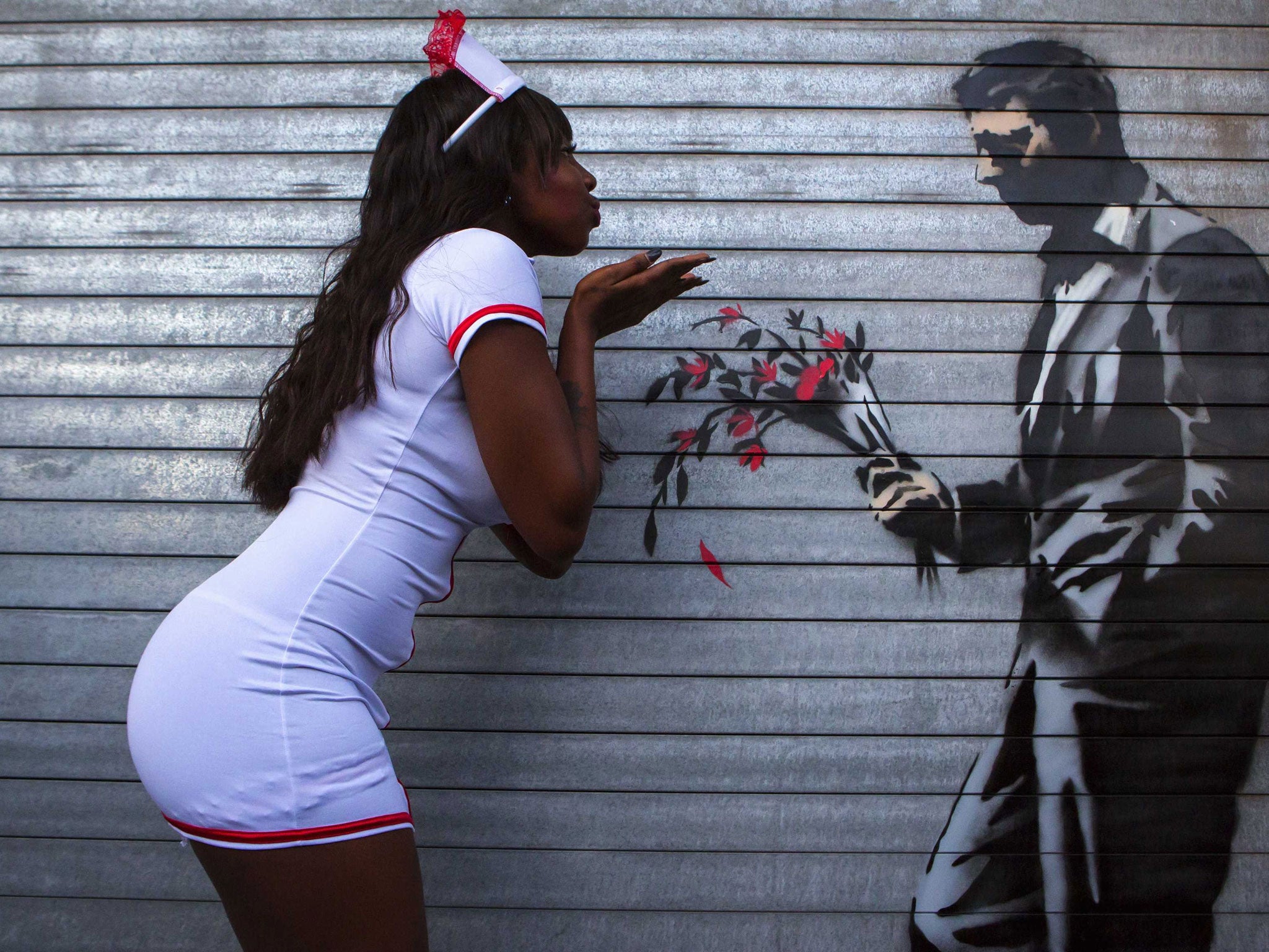 A dancer poses with a new piece of art by Banksy