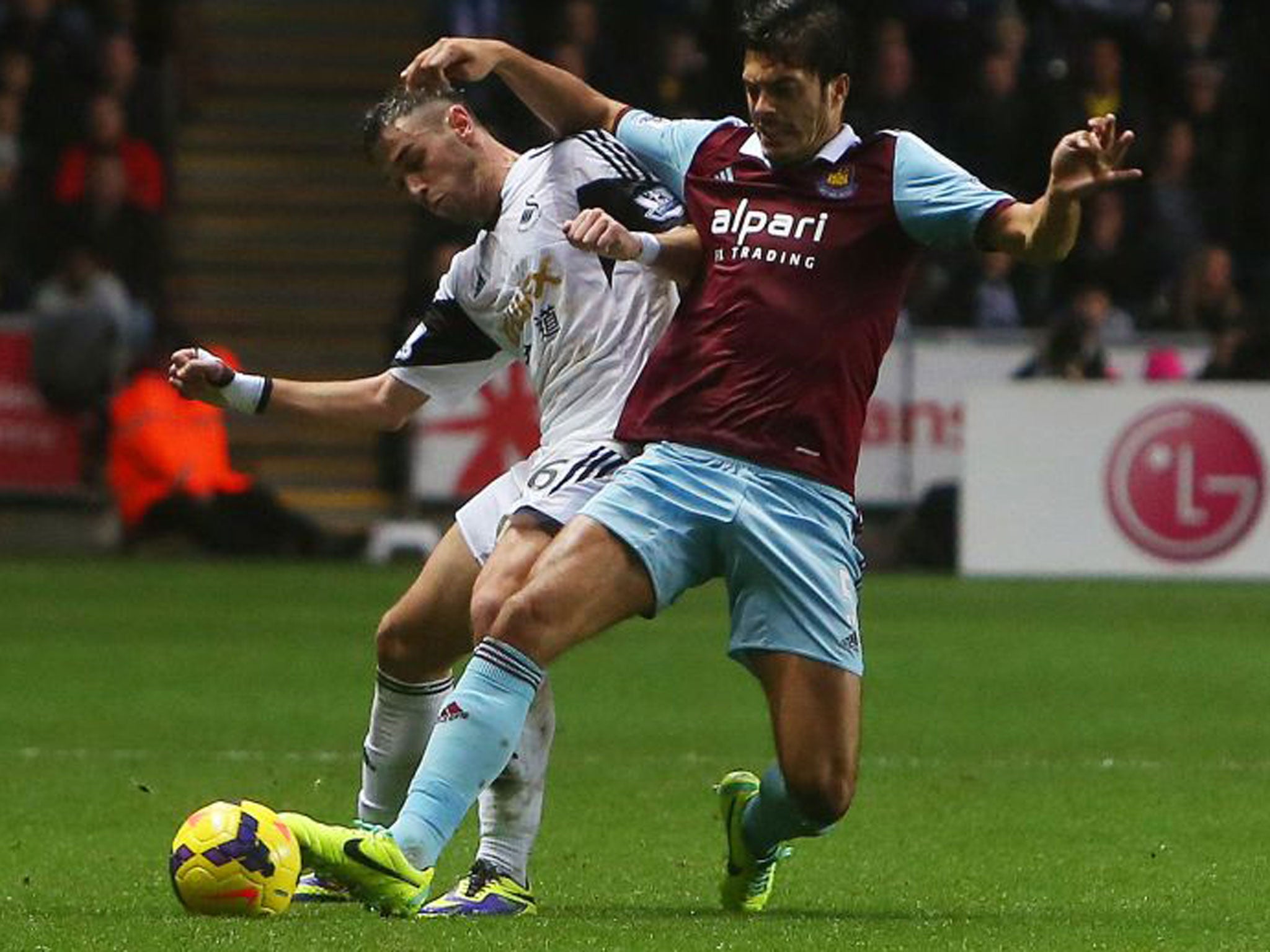 Swansea City's Spanish striker Alvaro Vazquez (left) vies with West Ham defender James Tomkins