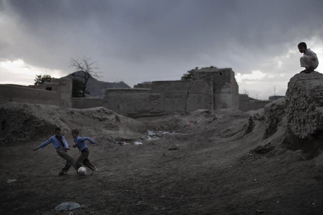 Two Afghan boys play soccer near ruins as the rain approaches at nightfall in the old part of Kabul, on April 10, 2010.