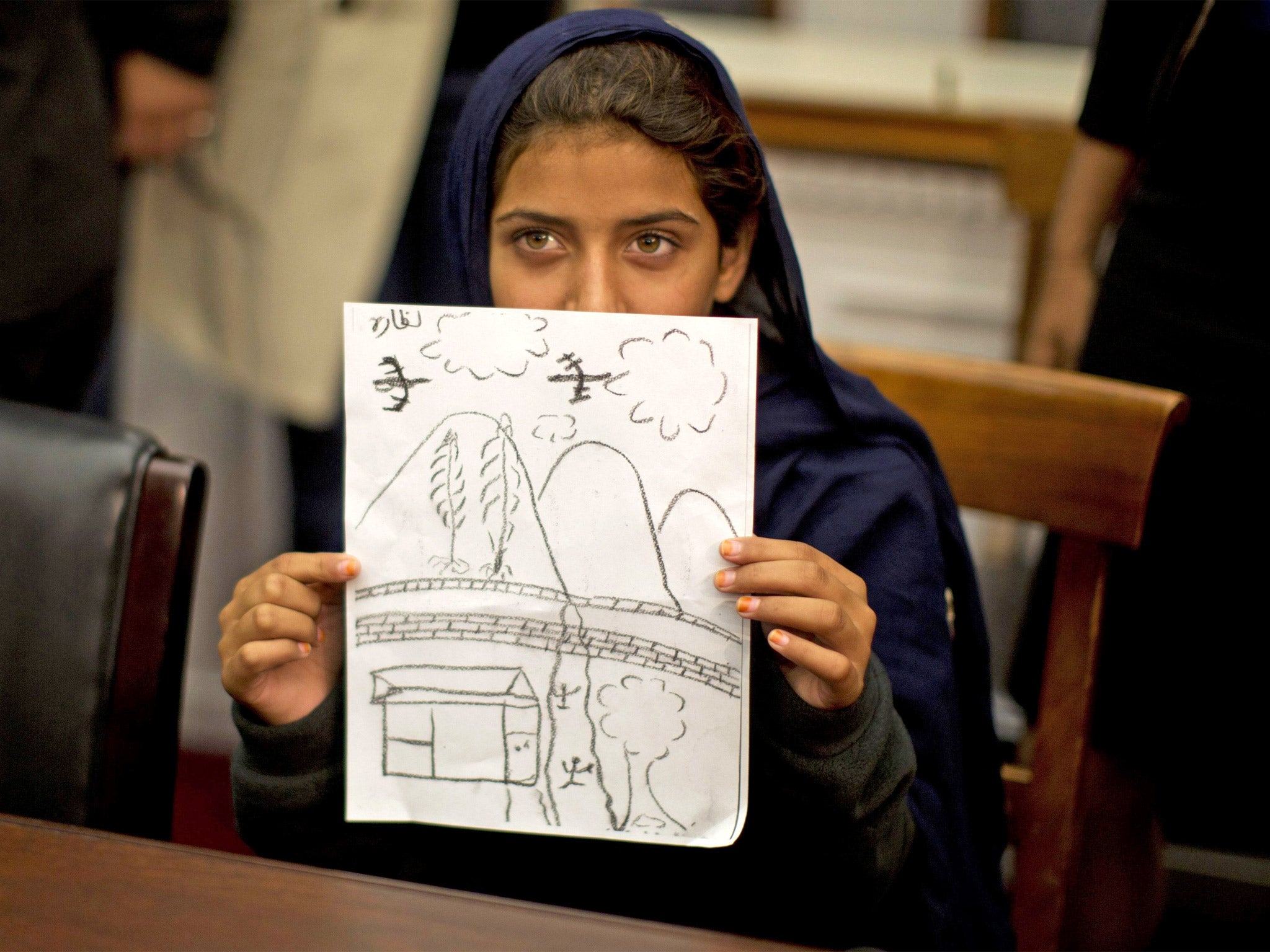 Nabila Rehman holds up a picture she drew depicting the drone strike on her village