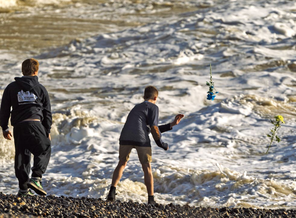 Friends of Dylan Alkins throw flowers into the sea in Newhaven, East Sussex, where the 14 year old vanished while playing in the surf