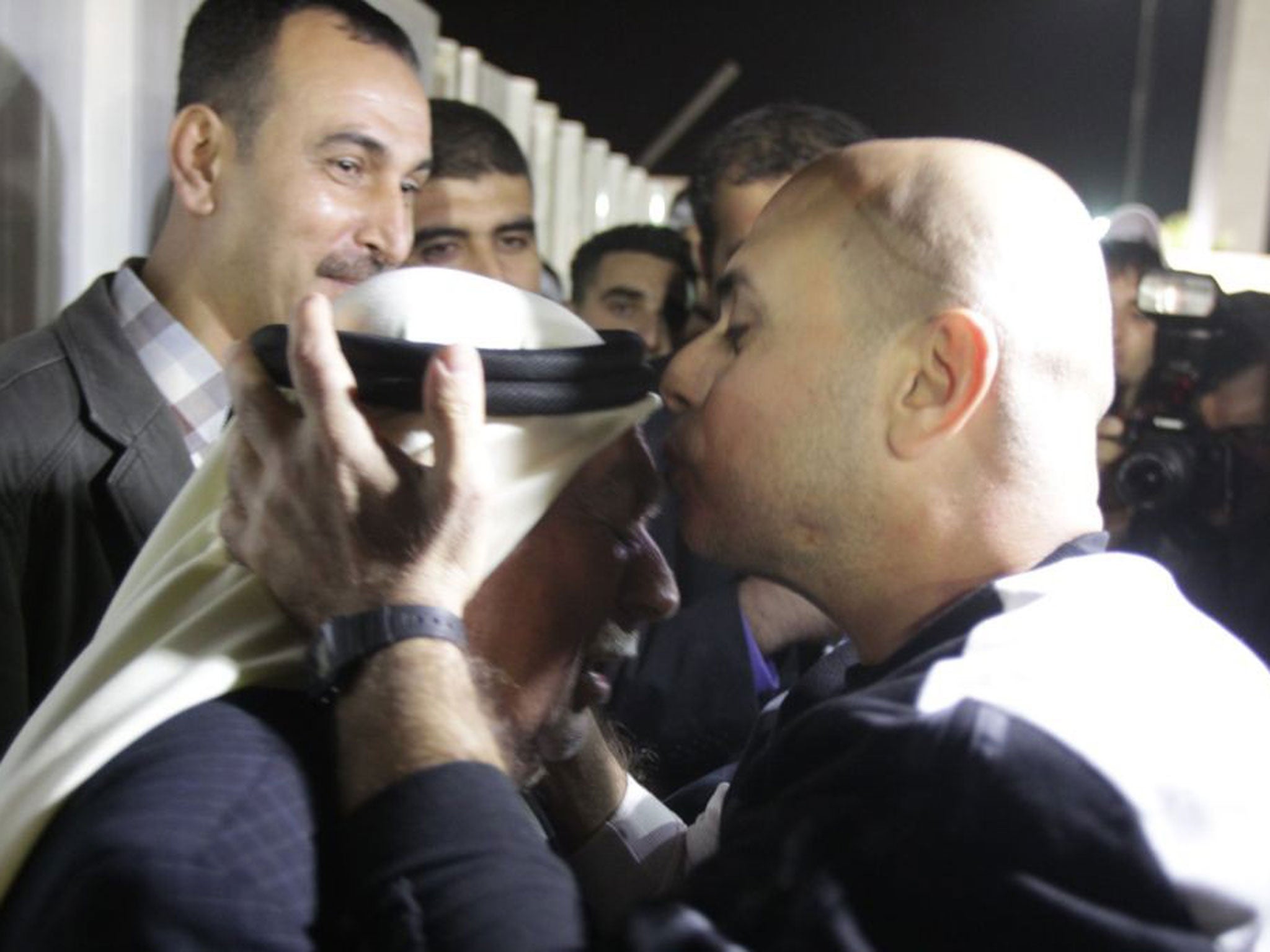 A released Palestinian prisoner kisses his father's head upon his arrival in the West Bank City of Ramallah, 30 October 2013