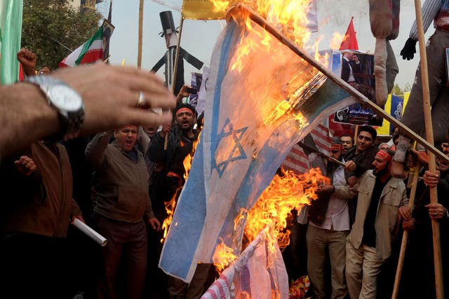 People burn Israel and U.S. flags a demonstration to mark the 34th anniversary of the 1979 US embassy takeover 