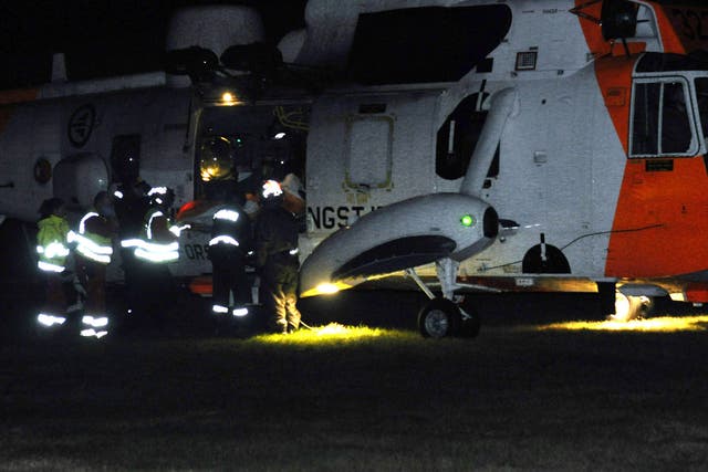 Emergency personnel surround a helicopter near the site of a bus hijacking in Aardal