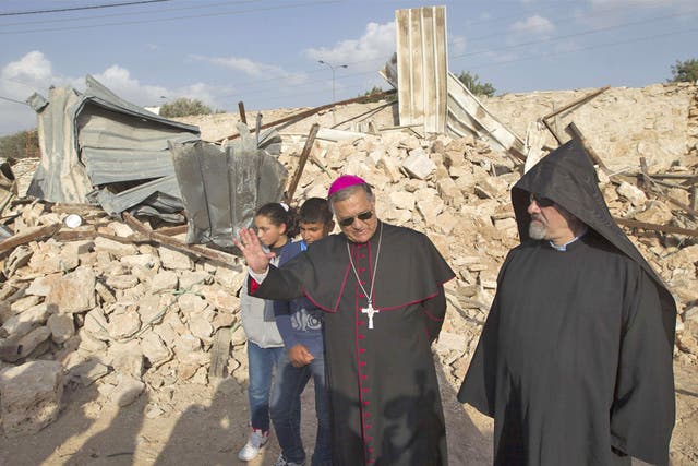 Children look on as Latin Patriarch of Jerusalem Fouad Twal (centre) stands amongst the ruins of a Palestinian home a week after it was demolished by the Israeli authority in East Jerusalem