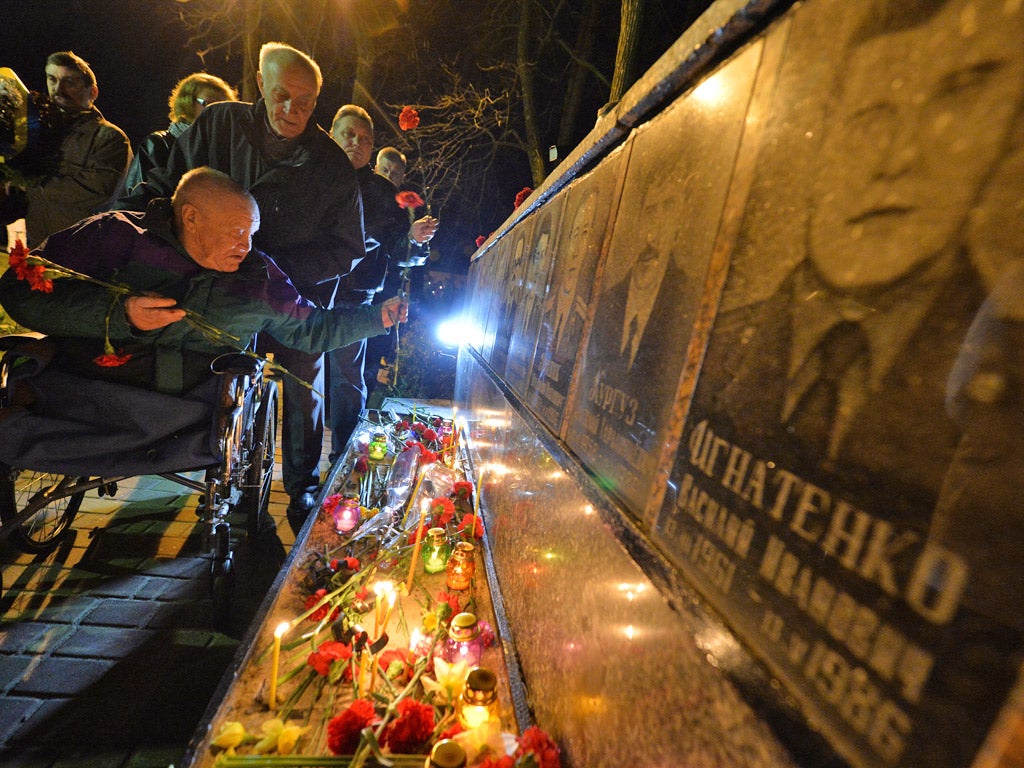 People lay flowers at a monument to Chernobyl victims (Getty)