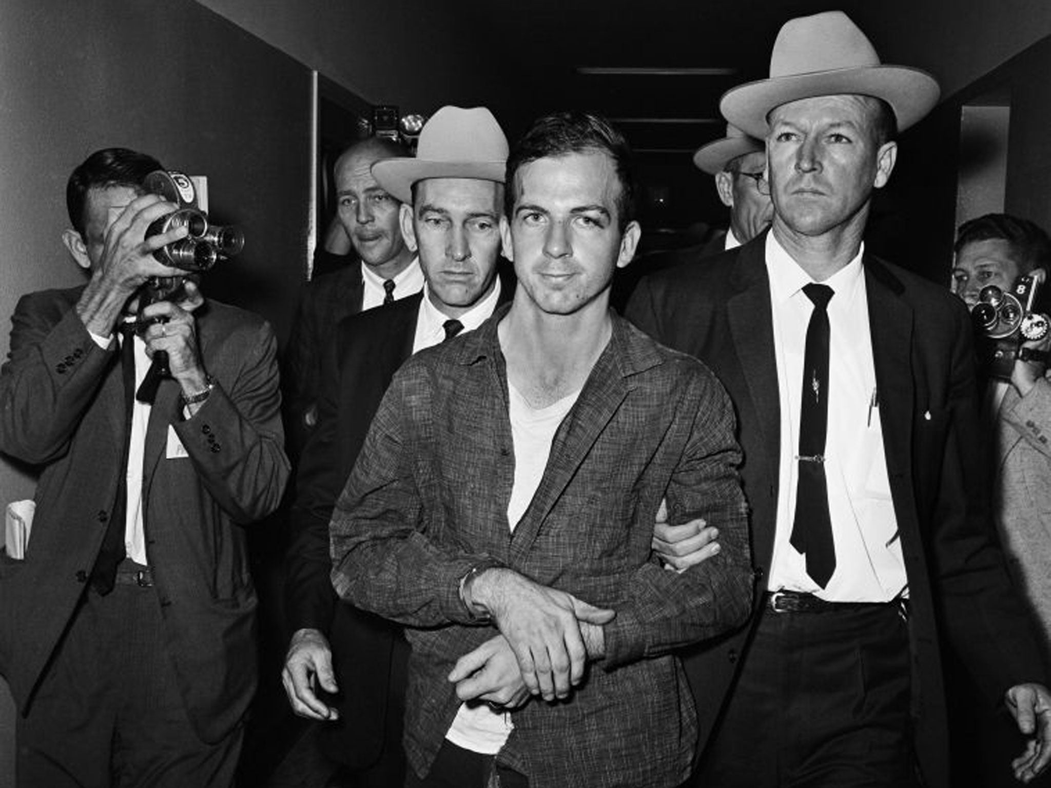 Lee Harvey Oswald escorted in handcuffs in the hallway of the Dallas Police Department