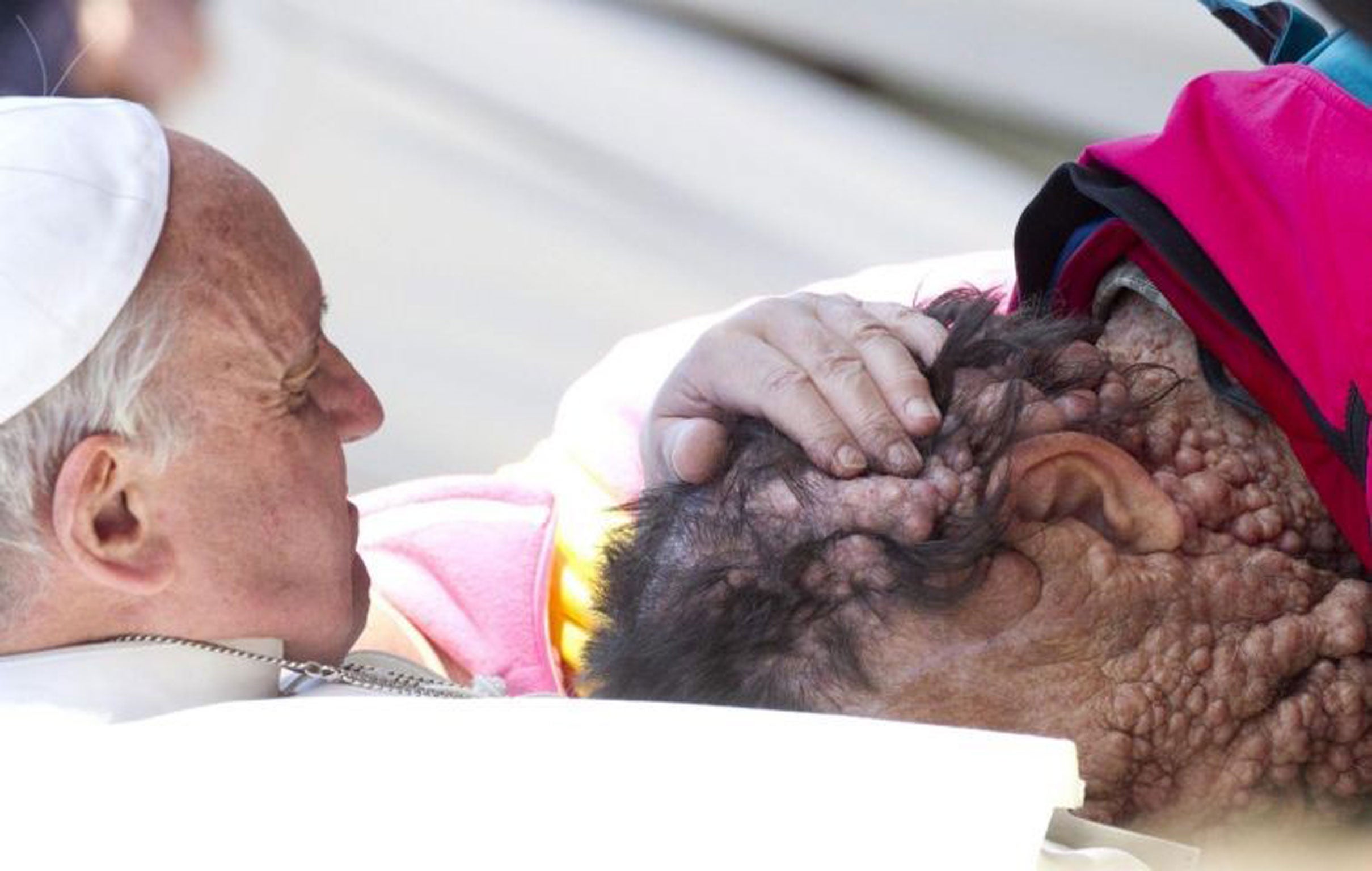 Pope Francis caresses a sick person in Saint Peter's Square at the end of his General Audience in Vatican City