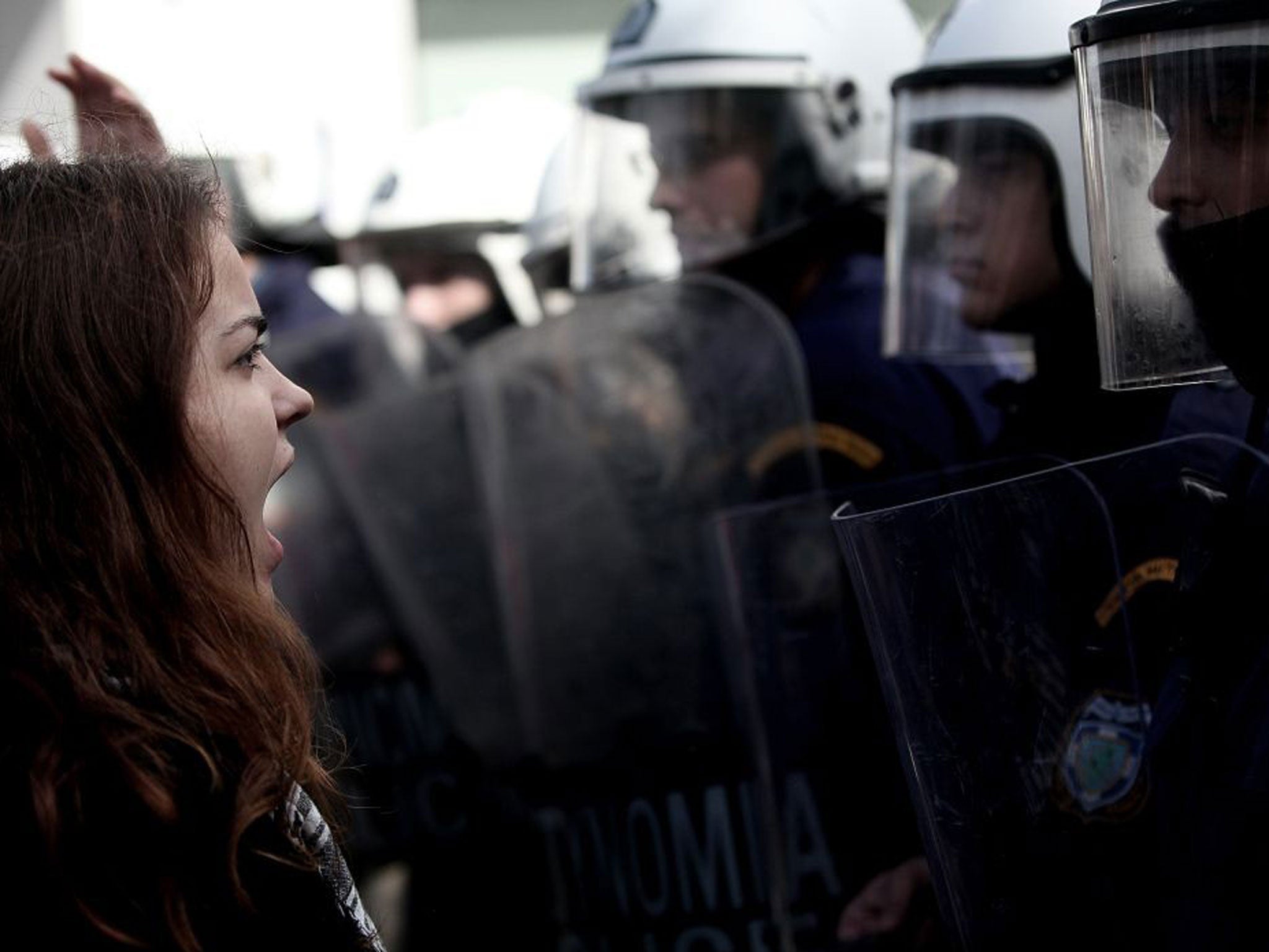 A demonstrator shouts at riot police on November 7, 2013 outside the headquarters of former public broadcaster ERT in Athens. Greek riot police burst into the headquarters of former public broadcaster ERT early on November 7 and forcibly removed employee