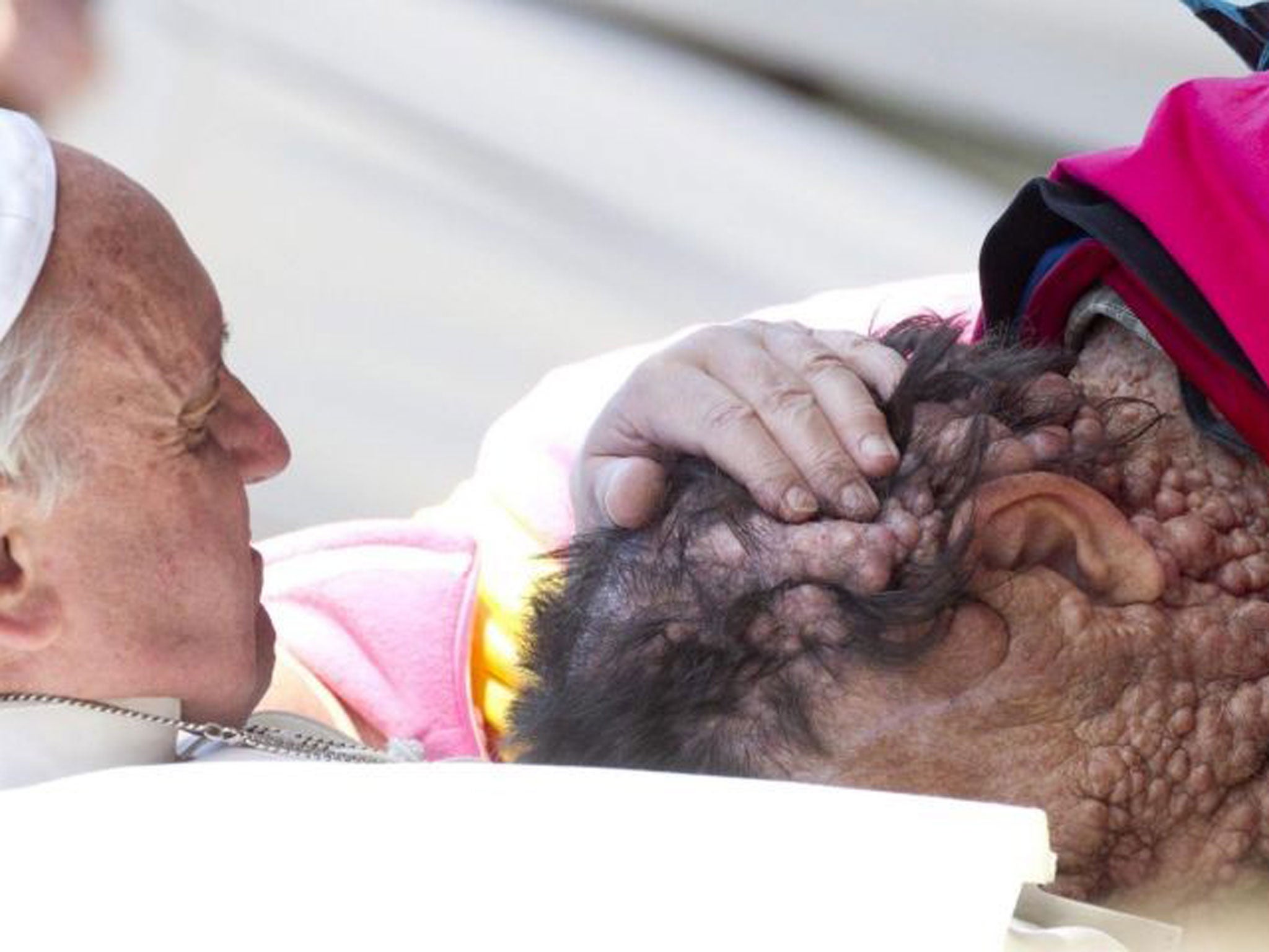 Pope Francis caresses a sick person in Saint Peter's Square at the end of his General Audience in Vatican City