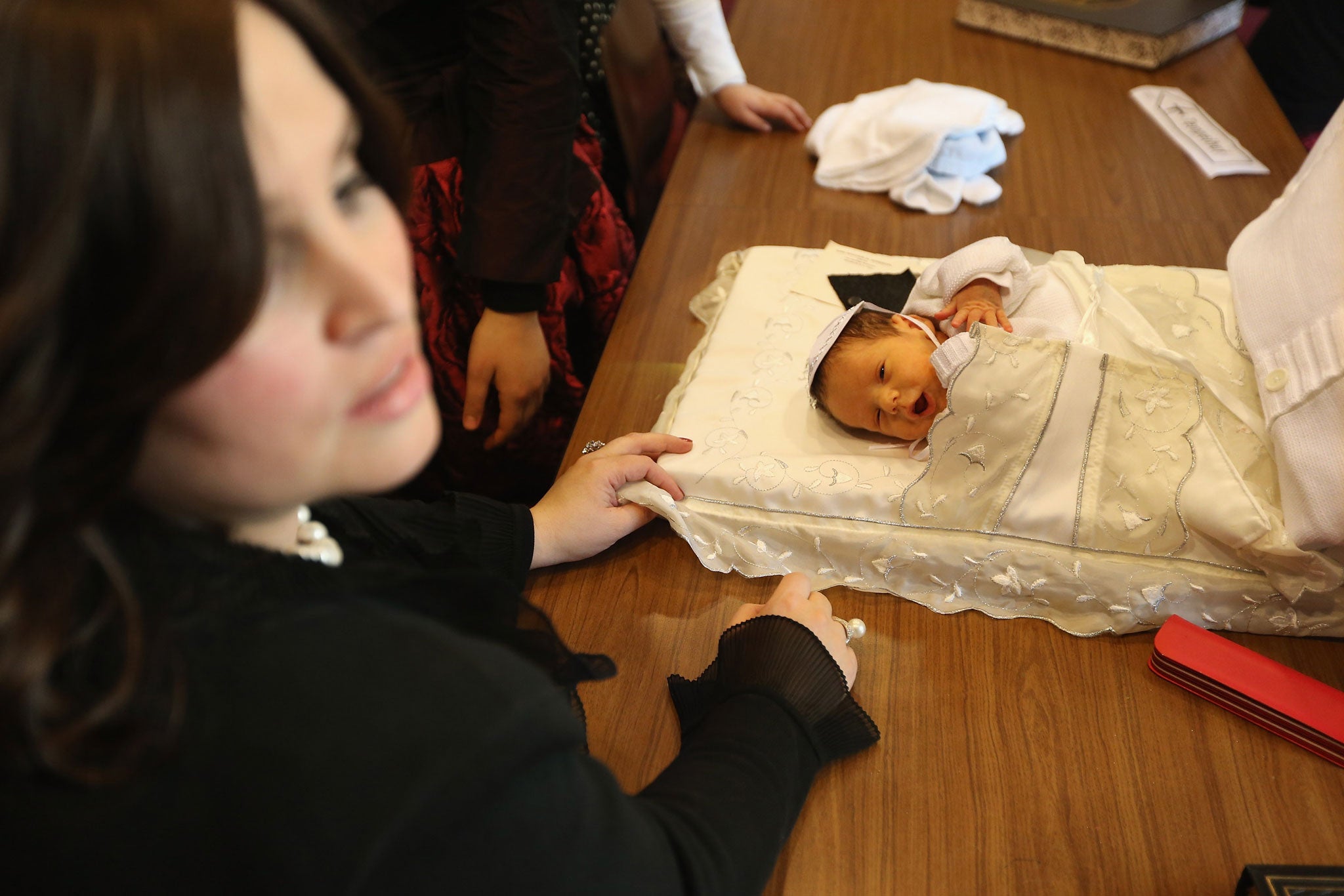 Orthodox Jewish women surround an infant following his circumcision ceremony