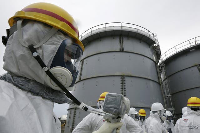 An official monitors radiation levels outside reactor four during a media tour of the Fukushima nuclear plant
