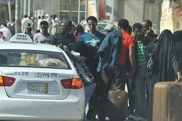 Foreign workers wait for a taxi to leave the Manfuhah neighbourhood of Riyadh on 10 November, after two people have been killed in clashes between Saudi and other foreign residents the previous day
