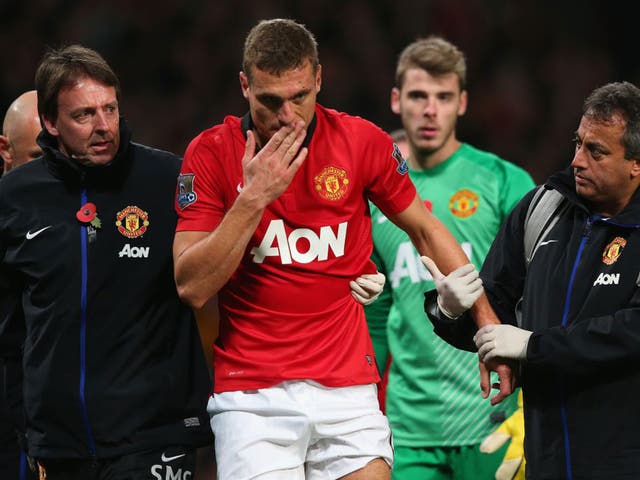 Nemanja Vidic of Manchester United is helped off the pitch