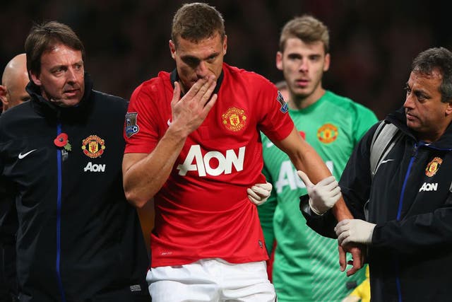 Nemanja Vidic of Manchester United is helped off the pitch