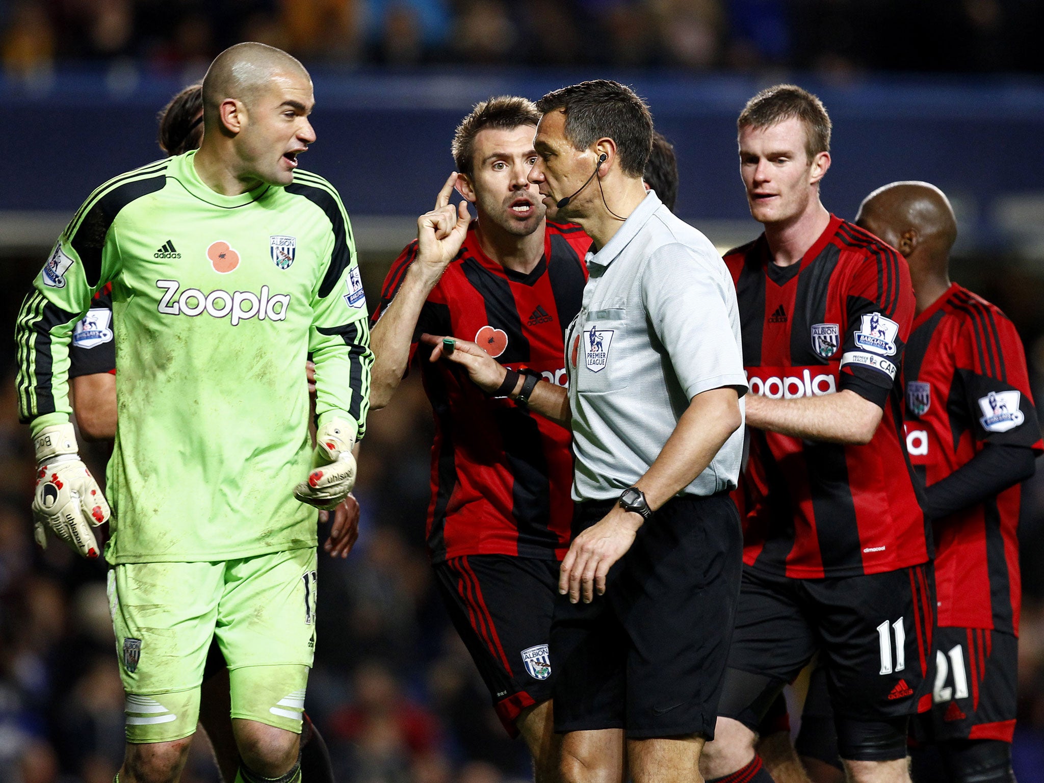 Referee Andre Marriner is surrounded by West Bromwich players after awarding Chelsea a late penalty