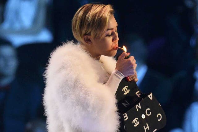 Miley Cyrus sparks controversy after she appeared to light a rolled-up joint on stage
