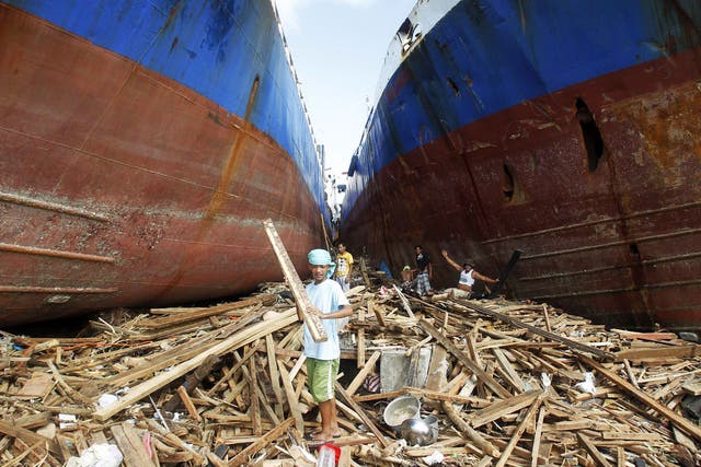 Survivors sift through debris between two cargo ships washed up by Haiyan
