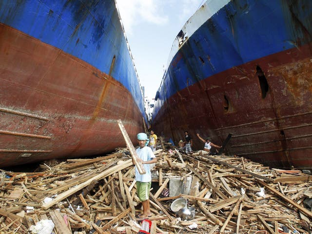 Survivors sift through debris between two cargo ships washed up by Haiyan